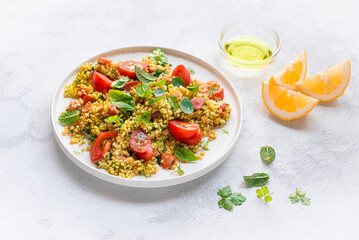 Tabbouleh o tabulè salad,  Arab dish from the Middle East and Mediterranean, with parsley, bulgur, onions, mint, tomatoes, seasoned with lemon juice, olive oil. White plate, front view