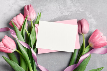 Blank paper greeting or invitation card mockup with fresh tulips flowers and envelope on grey