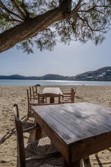 View of tables and chairs next to a tree at the Gialos Beach in Ios Greece