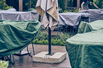 Tables and chairs are covered with covers in an empty outdoor cafe. The restaurant is closed for the night, outdoors. There are no visitors. With space to copy. High quality photo