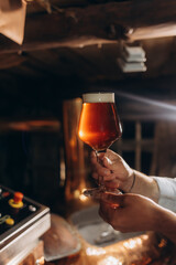 Mature man examining the quality of craft beer at brewery. Inspector working at alcohol manufacturing factory checking beer. Man in distillery checking quality control of draught beer