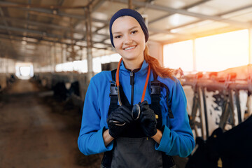 Portrait happy young woman veterinarian with phonendoscope on background barn with milk cows....
