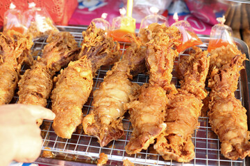 deep fried Crispy Whole squids on oil drain grille with customer choosing in street food  market 
