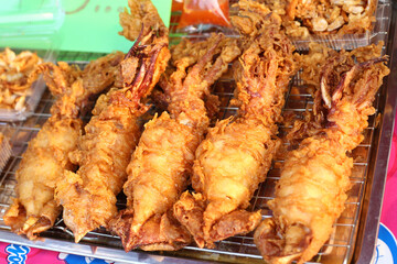 deep fried Crispy Whole squids on oil drain grille with customer choosing in street food  market 
