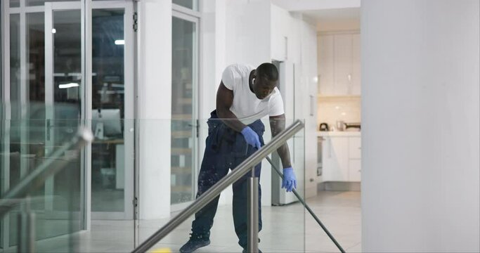 African man, cleaning and mopping office floor with earphones for work or company. Commercial cleaner, service and janitor maintenance in workplace for sanitary, employees and staff with chemical