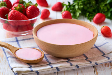 strawberry smoothie in a wooden bowl with fresh strawberry on a white table, selective focus.