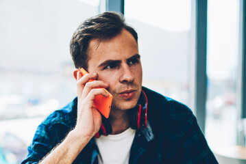 Young good looking male person communicating via smartphone connected to wireless internet while...