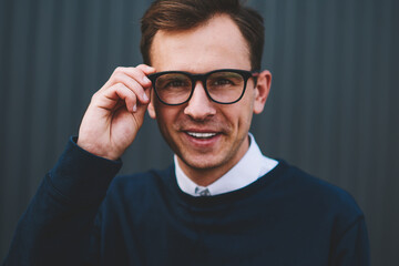 Half length portrait of young handsome smiling man in cool eyewear enjoying recreation at summer urban setting.Stylish successful hipster guy posing for camera while spending leisure time at street