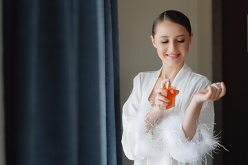 Happy young woman with makeup use perfume, radiant bride smiling. Concept morning and getting ready for wedding