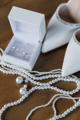 White Wedding Accessories: Shoes, Pearls, rings and Earrings on Wooden Table