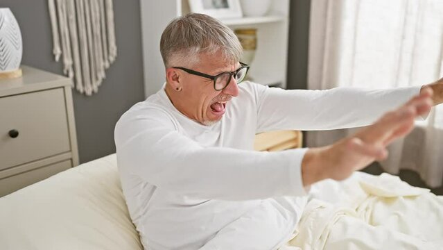 Terrified middle-aged grey-haired man in pyjamas, frantically shouting with fear expression, gesturing stop with hands in bedroom panic. shocking indoor horror concept.