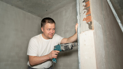 Young builder drilling holes on the wall