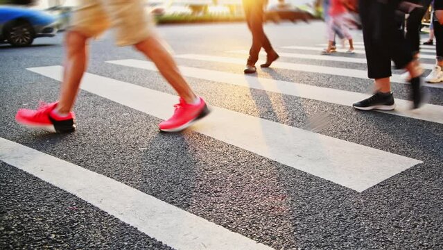 Group of people walking on the crosswalk at sunset