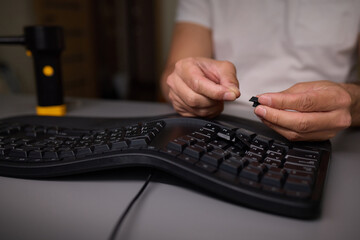 In a closeup shot, a hand is seen using a keycap puller tool to meticulously remove a keyboard key