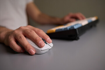 Person typing on keyboard and using a mouse at desk, focused on work technology