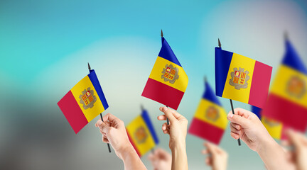 A group of people are holding small flags of Andorra in their hands.