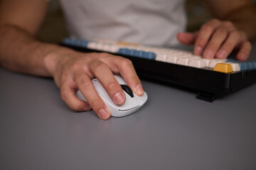 Person typing on keyboard and using a mouse at desk, focused on work technology