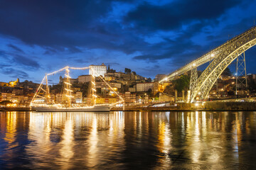 View of Porto city and Douro river with sailing ship from famous tourist viewpoint Marginal de Gaia riverfront in the evening. Porto, Vila Nova de Gaia, Portugal