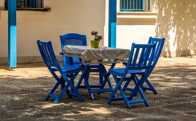 Blue wooden chairs and tables on a stone patio, surrounded by whitewashed walls in Side, Antalya, Turkey
