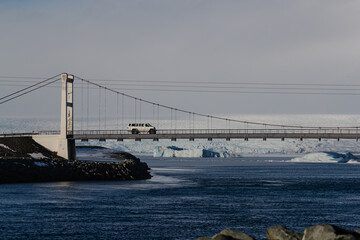 White SUV crossing a remote bridge over icy waters in the Arctic