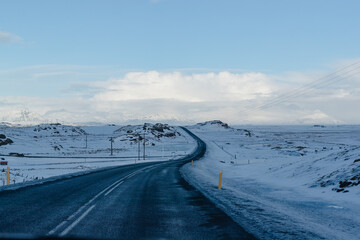 Snowy mountain road stretching into the distance under a clear blue sky