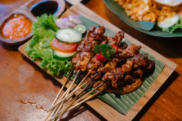 Skewered grilled chicken satay served with fresh vegetables and dipping sauces