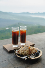 Iced coffee and almond croissant with mountain backdrop
