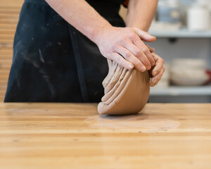 A potter kneads clay before using it in the workshop. Close-up of a man's hands. 