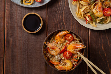 shrimp udon and rice vegetables pad thai sauce on the table next to soy sauce and chopsticks