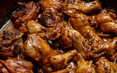 chicken breast pieces in a frying pan stewed in sauce.