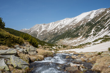 Vlahina river near its source in Vlahino lake running down the Pirin Mountains in late may.