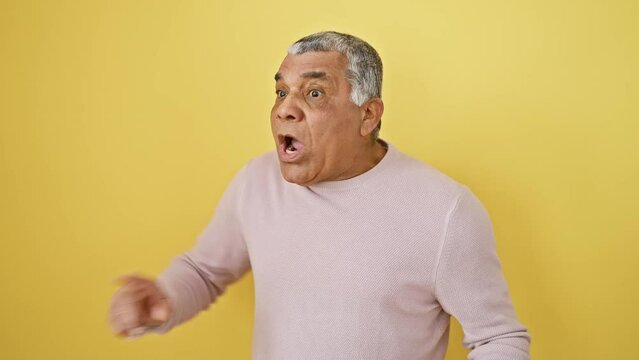 Enraged grey-haired middle age latin man furiously screaming, flaunting his rage in an aggressive stance. swathed in yellow, he's the picture of sheer frustration and unwanted anger.
