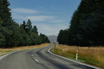 Straight road flanked by trees and fields