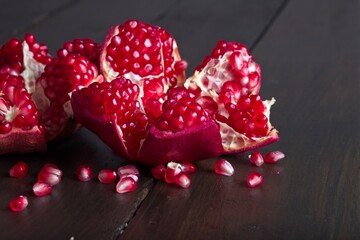 Close-up of ripe, fresh pomegranate cut open with view of seeds on a wooden table