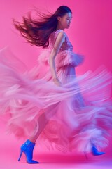 A dynamic image of a woman in motion, her hair and dress flowing against a vivid pink background