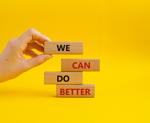 We Can Do Better symbol. Concept words We Can Do Better on wooden blocks. Beautiful yellow background. Businessman hand. Business and We Can Do Better concept. Copy space.