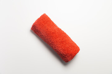Fluffy orange-red rolled up towel on white background