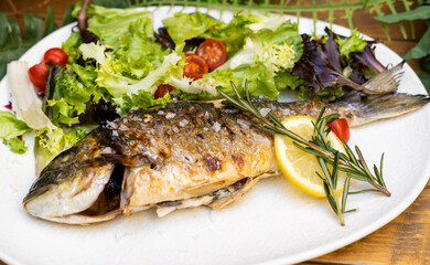 Un plato exquisito de dorada al horno con ensalada
