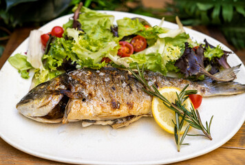 Un plato exquisito de dorada al horno con ensalada
