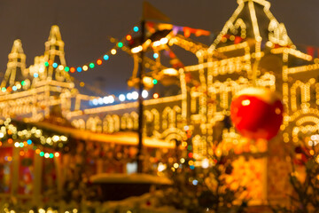 Defocused colorful houses on Christmas Fair in winter with lots of lights and bokeh on snowy evening