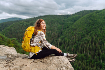 Naklejka premium Tourist woman on the peak of high rocks. Sport and active life concept. Active woman enjoys the beautiful scenery of the majestic mountains. Travel, adventure.