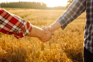 Handshake two farmer on the background of a wheat field at sunset. The concept of the agricultural...