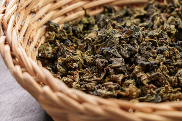Dry rolled gunpowder green tea leaves in an eco rustic rattan bowl on a board. Healthy herbal drinks. Source of Antioxidants. 