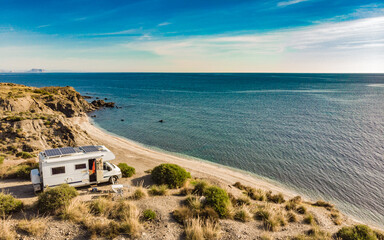 Caravan with solar panels on roof camp on sea, Spain. Aerial view.
