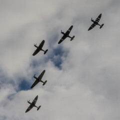 A flight of five WW2 fighter aircraft silhouetted against the sky.
