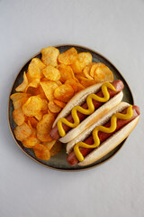 Homemade Hot Dog with Mustard and Potato Chips on a Plate, top view.