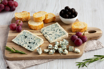 Organic Blue Cheese with Grapes and Olives on a Wooden Board, side view.