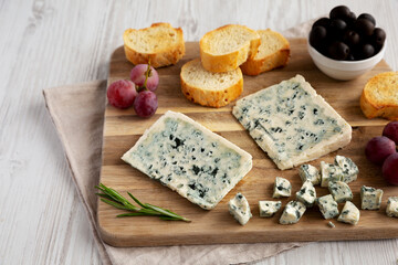 Organic Blue Cheese with Grapes and Olives on a Wooden Board, side view.
