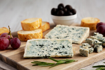Organic Blue Cheese with Grapes and Olives on a Wooden Board, side view.