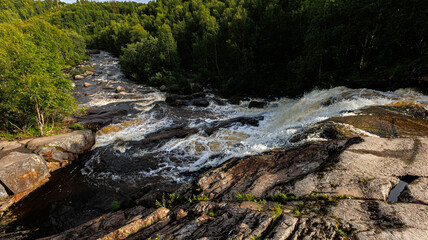 A picturesque waterfall is encompassed by lush trees and weathered rocks